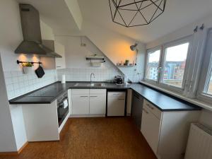 a kitchen with white cabinets and black counter tops at Süße Marie 18 - Coffee for free - in Karlsruhe