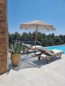 a patio with an umbrella and chairs and a pool at Villa Westwood in Parga