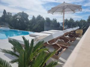 a resort pool with lounge chairs and an umbrella at Villa Westwood in Parga
