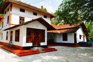 a small white house with a red roof at Vilayara Heritage Retreat -Kozhikode in Kunnamangalam