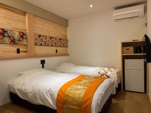 a bedroom with two beds and a tv in it at Besso城前 in Himeji