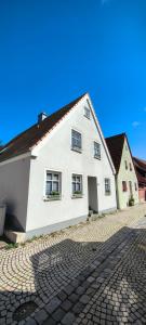 a white house with two windows on a cobblestone street at FeWo Altstadt Herrieden in Herrieden