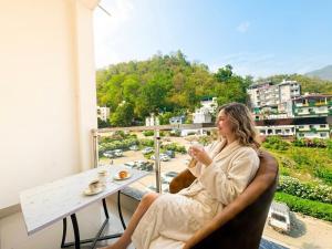 a woman sitting at a table on a balcony at Hotel Mahadev Tapovan in Rishīkesh +40 photos