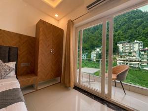 a bedroom with a large window with a chair at Hotel Mahadev Tapovan in Rishīkesh