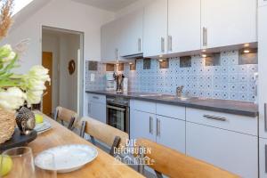 a kitchen with white cabinets and a wooden table at Box-10 in Büsum