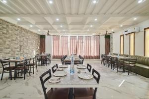 a dining room with tables and chairs and a brick wall at Treebo Chanakya Palm in Chhatikara