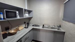 a small kitchen with a sink and a microwave at GROOTVALLEI SELF CATERING Units in Mahikeng