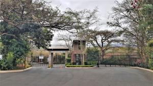 an empty parking lot with a gate and trees at The Urban Nest in Nelspruit