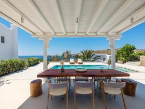 a patio with a table and chairs and a swimming pool at myMykonos Villa I in Platis Gialos