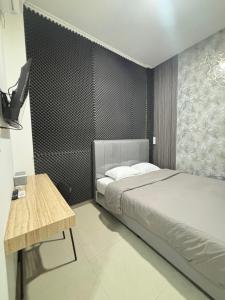 a bedroom with a bed and a desk and a television at Lovisya Residence in Jakarta +5 photos