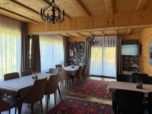 a dining room with tables and chairs and windows at Guesthouse Demushi in Valbonë