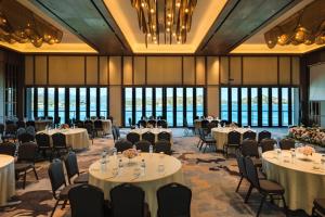 a banquet hall with tables and chairs and windows at Katamaran Hotel & Resort Komodo in Labuan Bajo
