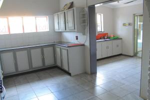 a kitchen with white cabinets and a tile floor at One love suites in Mokopane