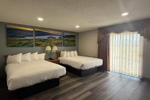 a hotel room with two beds and a window at Days Inn by Wyndham Medford in Medford