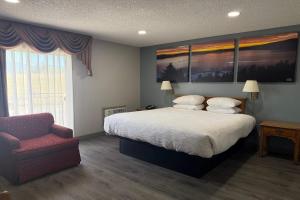 a bedroom with a large bed and a chair at Days Inn by Wyndham Medford in Medford