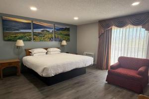 a bedroom with a bed and a chair at Days Inn by Wyndham Medford in Medford