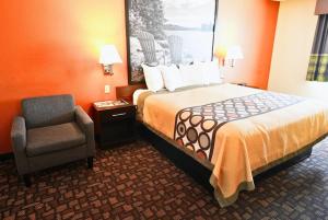 a hotel room with a bed and a chair at Super 8 by Wyndham Clive IA in Clive +8 photos