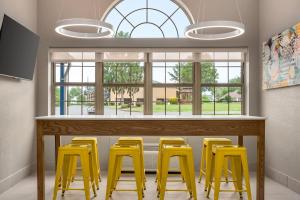 a bar with yellow stools in a room with windows at Microtel Inn & Suites by Wyndham Culpeper in Culpeper