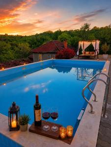 a pool with wine glasses and a bottle of wine at "Бадевски рай" Къща за гости ВЯРА in Elena