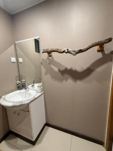 a bathroom with a sink and a branch on the wall at Hanivai Beach Bungalow in HUH