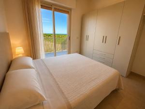 a bedroom with a white bed and a large window at Oasi Frontemare Appartamenti in Pineto
