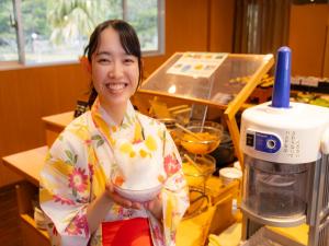 a woman holding a bowl of food in a kitchen at Kyukamura Ibusuki in Ibusuki