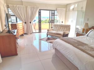 a bedroom with a bed and a chair and a television at 17 Villa Leadwood in Jeffreys Bay
