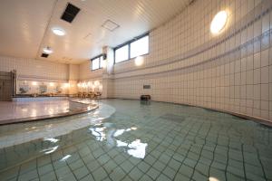 a swimming pool with water in a room with tiled walls at Castle Inn Komaki in Komaki
