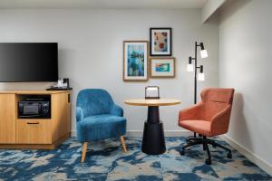 a room with two chairs and a table and a tv at Hampton Inn Oak Ridge Knoxville in Oak Ridge