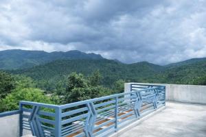 a blue bench on a balcony with mountains in the background at Sindu Homestay in Kalasa +6 photos