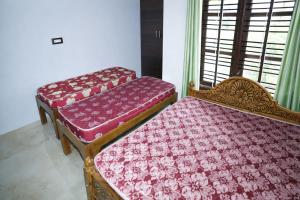 a bedroom with two beds with red cushions at Sindu Homestay in Kalasa