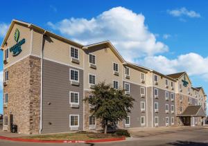 a large apartment building with a tree in front of it at WoodSpring Suites Abilene in Abilene