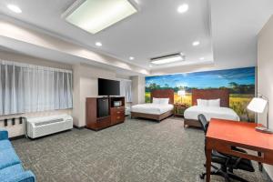a hotel room with two beds and a desk at Clarion Pointe Starkville near University in Starkville