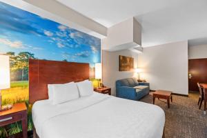 a hotel room with a bed and a couch at Clarion Pointe Starkville near University in Starkville