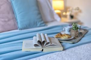 a book and a plate of food on a bed at Boutique Hotel Sant'Andrea & Relais in San Pantaleo +40 photos