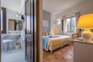 a bedroom with a bed and a bathroom with a sink at Boutique Hotel Sant'Andrea & Relais in San Pantaleo