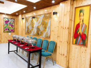 a dining room with a table and chairs and a painting at Malti Guest House in Kullu Manali