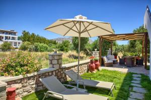 a patio with two chairs and an umbrella at Haraki Stone Apartments in Haraki