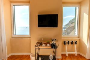a living room with two windows and a flat screen tv at Orto al Mare Room Rental in Riomaggiore