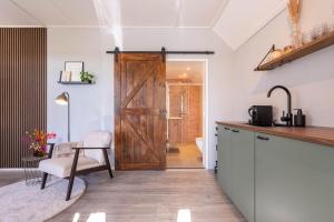 a kitchen with a sliding barn door and a chair at Hoeve Hunzedal in Eexterzandvoort