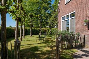 a fence in front of a brick house with trees at Hoeve Hunzedal in Eexterzandvoort