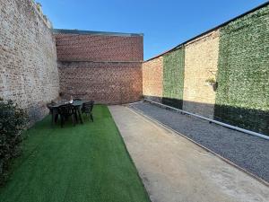 a patio with a table and chairs next to a brick wall at Le Saint Sauveur - centre ville in Péronne +3 photos