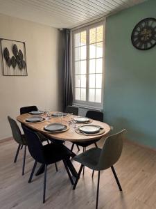 a dining room table with chairs and a clock on the wall at Le Saint Sauveur - centre ville in Péronne