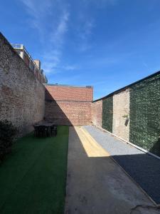 a courtyard with a table in a brick wall at Le Saint Sauveur - centre ville in Péronne