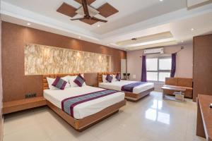 a bedroom with two beds and a ceiling fan at Devbhoomi Inn in Deoghar +49 photos