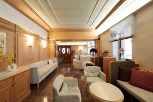 a waiting room with couches and chairs in a room at Hotel Centrale in Auronzo di Cadore