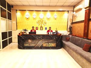 three people sitting at a welcome sign in a lobby at Buddha Heritage in Patna