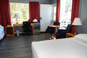 a hotel room with a bed and a desk and chairs at Rodeway Inn in Grand Falls +21 photos