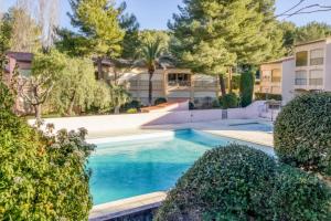 a swimming pool in a yard with trees and buildings at Flat With Swimming Pool Near The Beach in Sanary-sur-Mer
