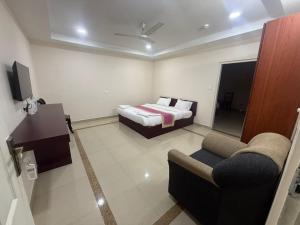 a bedroom with a bed and a couch and a tv at Staio Rooms in Thodupuzha